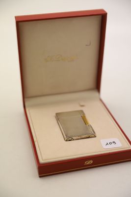 un briquet argenté dans une boîte rouge posée sur une table blanche