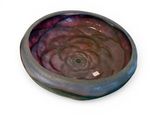 a bowl with a purple swirl in it on a white surface