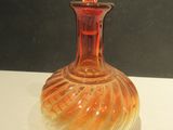 a red glass bottle with a swirly design on it