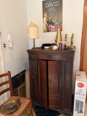 a wooden cabinet in the corner of a room next to a chair