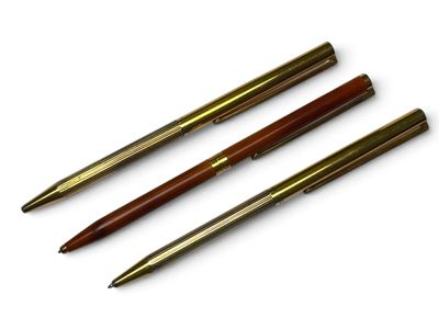trois stylos sont alignés les uns au-dessus des autres sur une surface blanche