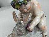 a figurine of a boy riding a donkey with grapes on his head
