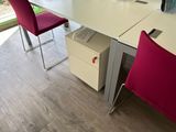 two red chairs sitting at a white desk with a laptop on it