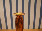 a brown vase with a yellow flower in it on a table