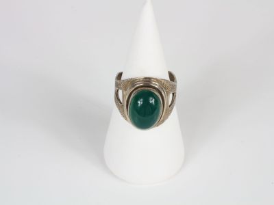 a close up of a ring with a green stone on a white cone