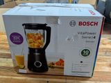 boxed box of a blender sitting on a table with a glass of orange juice in it