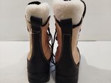 pair of black and tan boots with fur lined up on a white surface