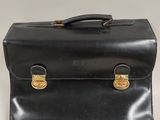 an old black briefcase sitting on top of a white table