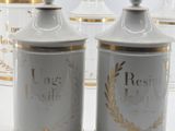 three white and gold canisters sitting on top of a white table