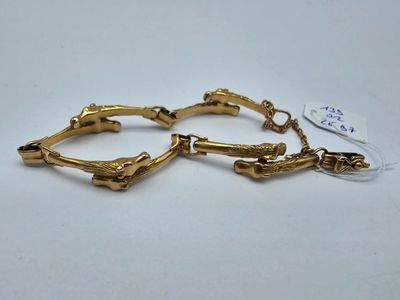une paire de bracelets en or posés sur une surface blanche