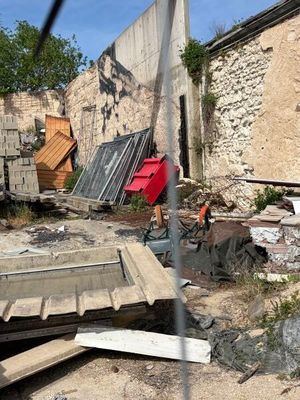 un homme qui se tient devant un immeuble, un parapluie rouge à la main