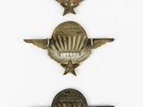 three small metal badges on a white surface with a white background