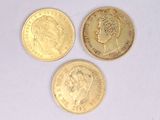 trois types différents de pièces d'or posées sur une surface blanche