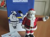 une figurine du Père Noël posée sur une table, à côté d'une boîte de miniatures Michel