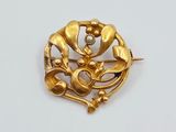 une broche en or ornée d'une perle au centre