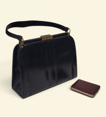 a black purse and a cell phone on a white surface