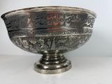 silver plated bowl with floral designs on it on a white surface