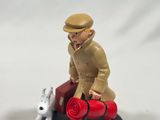 a figurine of a man sitting on a motorcycle with a dog