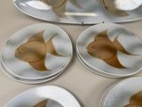 four plates with fish designs on them sitting on a table