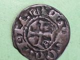 a close up of a coin with a cross on it on a green surface