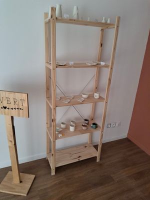 a wooden shelf with cups on it in the corner of a room