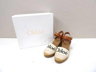 Les chaussures sont posées sur la table, à côté d'une boîte blanche.