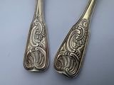 pair of antique silverware spoons with ornate designs on them
