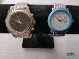 two watches that are sitting on a black stand