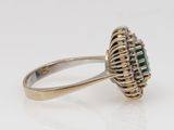 a close up of a ring with a green stone surrounded by diamonds