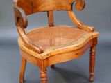 une vieille chaise en bois avec une assise tressée posée sur une surface grise