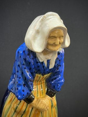 une figurine représentant une vieille femme assise sur un tabouret