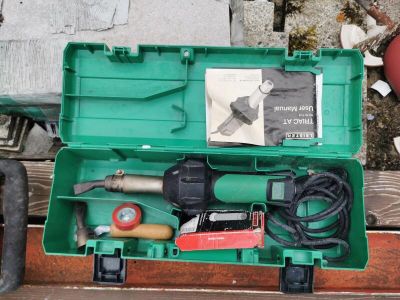 a green box with tools in it sitting on a wooden table