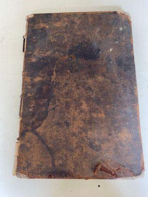 un vieux livre posé sur une table blanche, à côté d'une paire de ciseaux