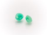 a pair of green glass beads on a white surface