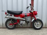 une petite moto rouge garée devant un immeuble
