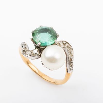 a close up of a ring with a pearl and a green stone