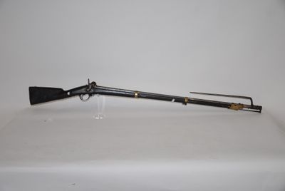 an old rifle on a white table with a black handle