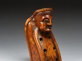 une vieille figurine en bois représentant une tête d'homme, posée sur un socle