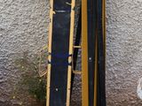 des skis jaunes et noirs appuyés contre un mur, à côté d'une borne d'incendie