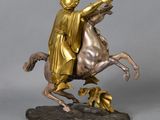 bronze statue of a man riding a horse with a golden robe