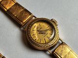 a gold watch sitting on top of a table next to a bracelet