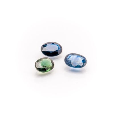 three blue and green tourmaline gems on a white background