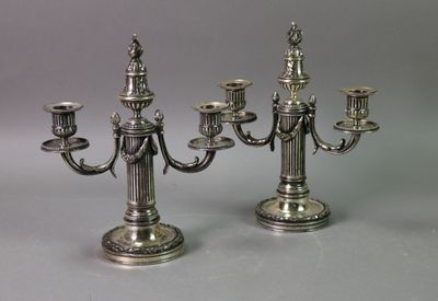 two silver candelabs are sitting on a table next to each other
