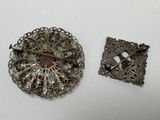 two antique brooches and a broochet on a white surface