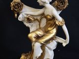 statue d'une femme assise sur un rocher, tenant un bouquet de roses