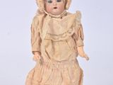 une poupée à l'ancienne, coiffée d'un bonnet et vêtue d'une robe, posée sur un fond blanc