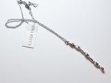 une chaîne en argent avec un pendentif, posée sur une surface blanche