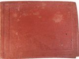 an old red book sitting on top of a white surface