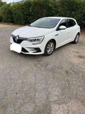 a white car parked in a parking lot next to a hedge