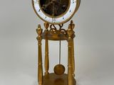 une horloge dorée avec un cadran blanc, posée sur un socle